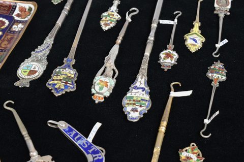 A collection of coloured enamel terminal souvenir button hooks and loops