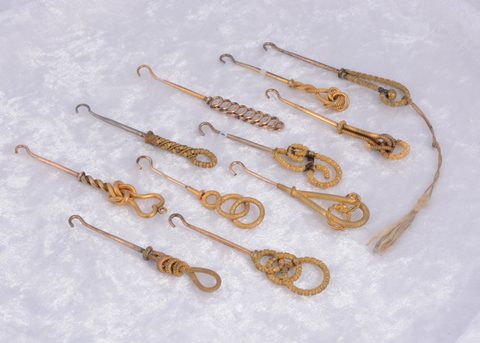 A collection of eleven textured knot design gilt metal button hooks