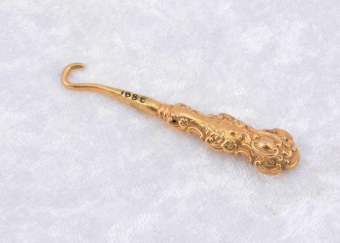A Victorian 9ct gold floral embossed button hook