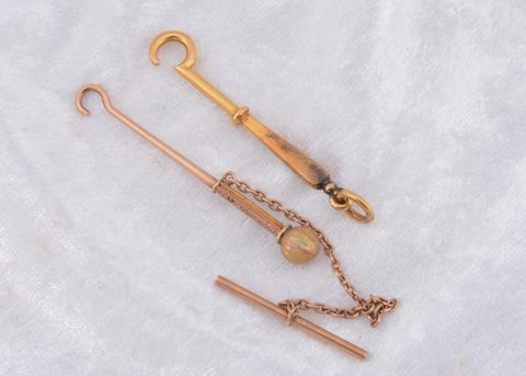 A yellow metal T bar fob button hook