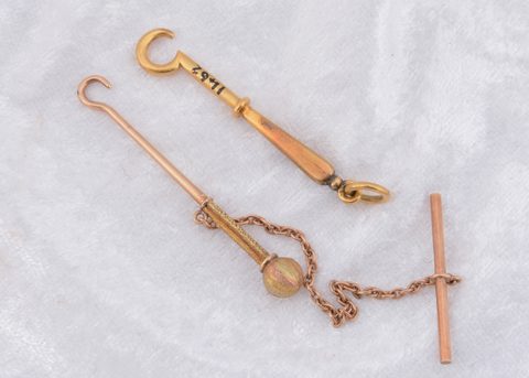 A yellow metal T bar fob button hook