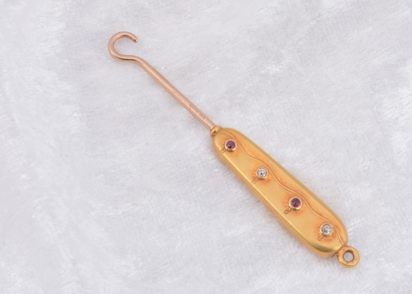 An Art Deco Tiffany & Co. gold button hook set with rubies and diamonds