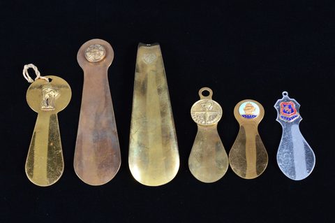 Five brass and one steel commemorative or souvenir shoehorns