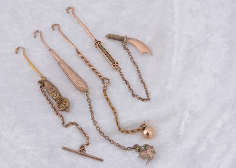 Four various lapel button hooks