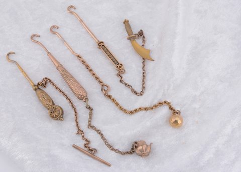 Four various lapel button hooks