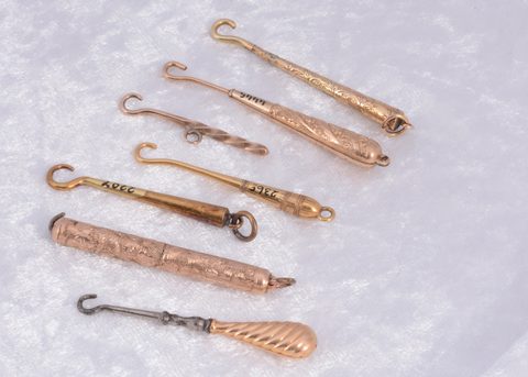 Seven unmarked yellow and gilt metal button hooks