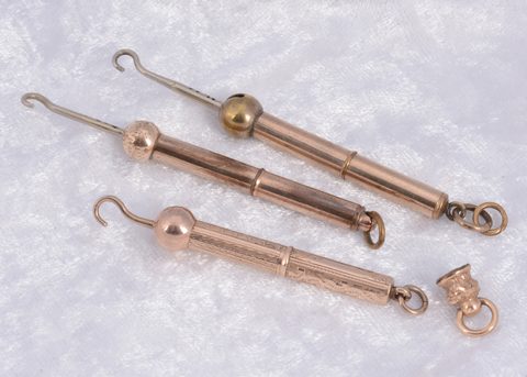 Three gilt metal protracting button hooks