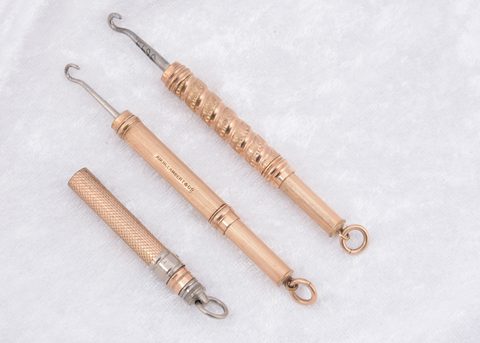 Three gold plated cylindrical sliding button hooks