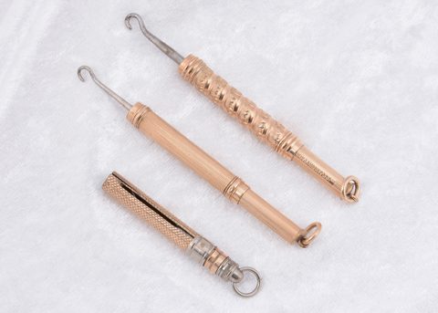 Three gold plated cylindrical sliding button hooks