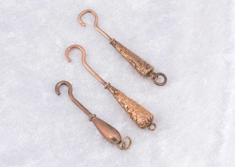 Three miniature yellow metal and steel button hooks
