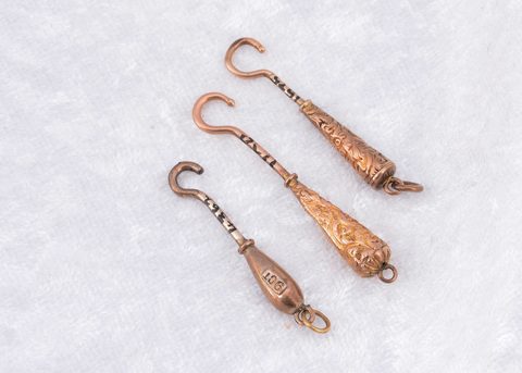 Three miniature yellow metal and steel button hooks