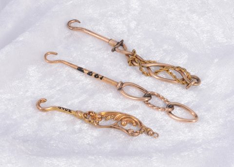 Three ornate yellow and gilt metal button hooks