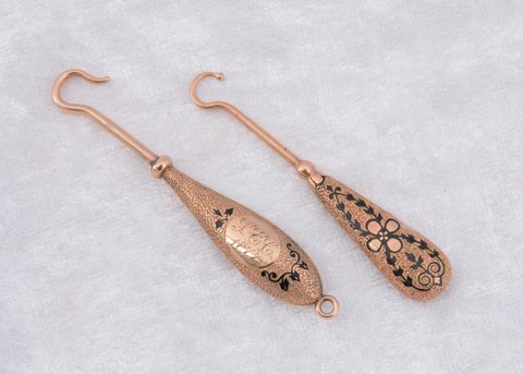 Two continental yellow metal and enamel fixed button hooks